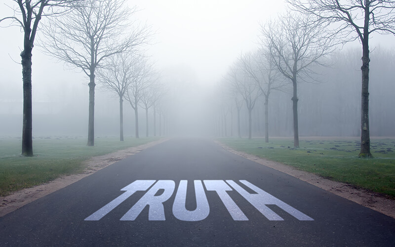 foggy scene with "TRUTH" painted on the road